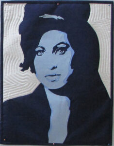 An Art Quilt portrait of a female Singer in black and blue monotone shades against a white background