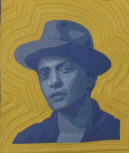 An Art Quilt portrait of a male Singer in blue monotones against a yellow background.