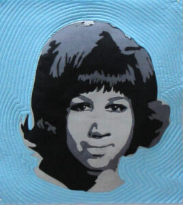 An Art Quilt portrait of a female singer in monotones against a blue background.