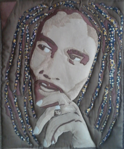 An Art Quilt of a male Singer with dreadlocks with his hand to his chin as if he is reflecting on life.